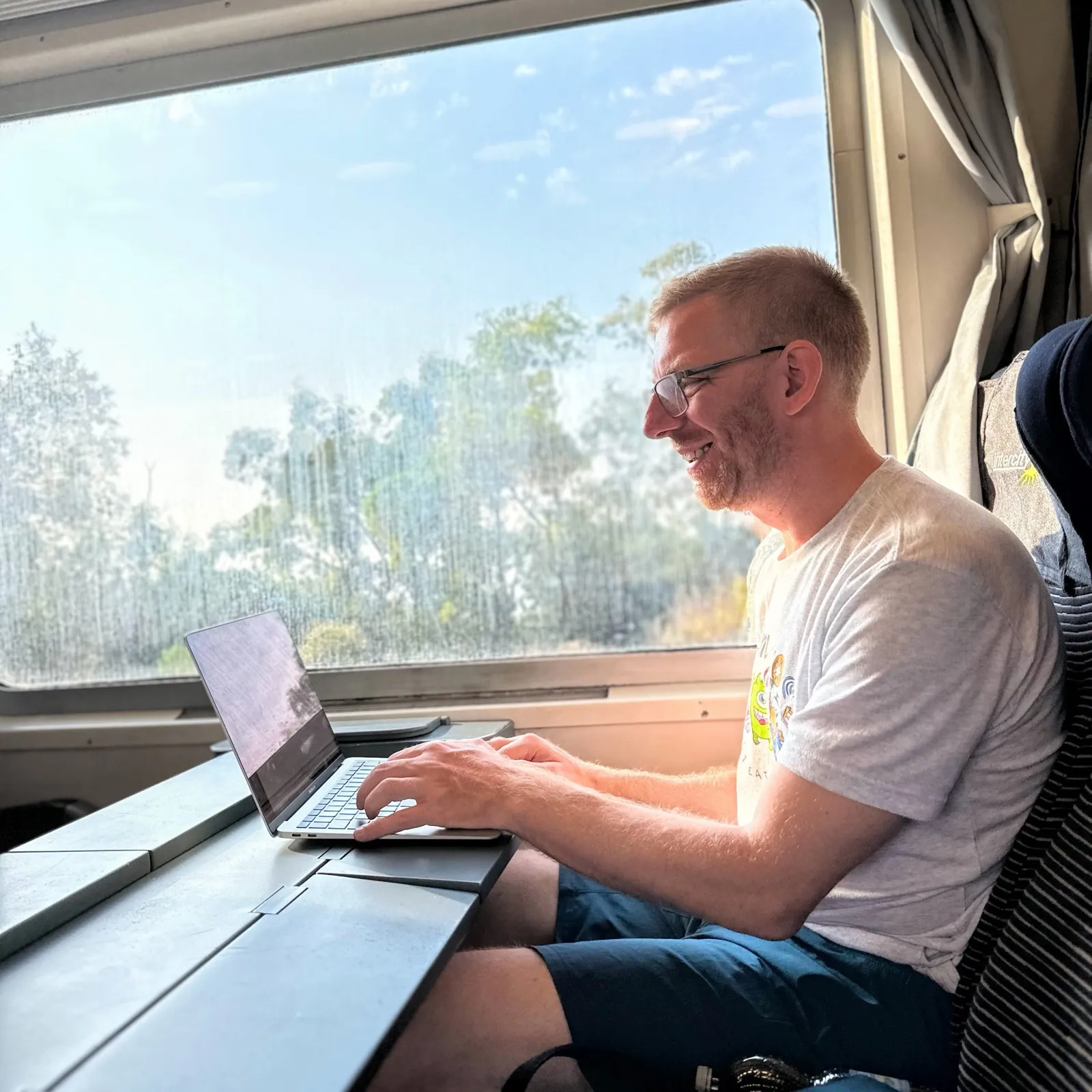 Chris writing on his laptop on a train
